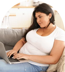 A woman sitting on a couch, looking relaxed and comfortable on a laptop