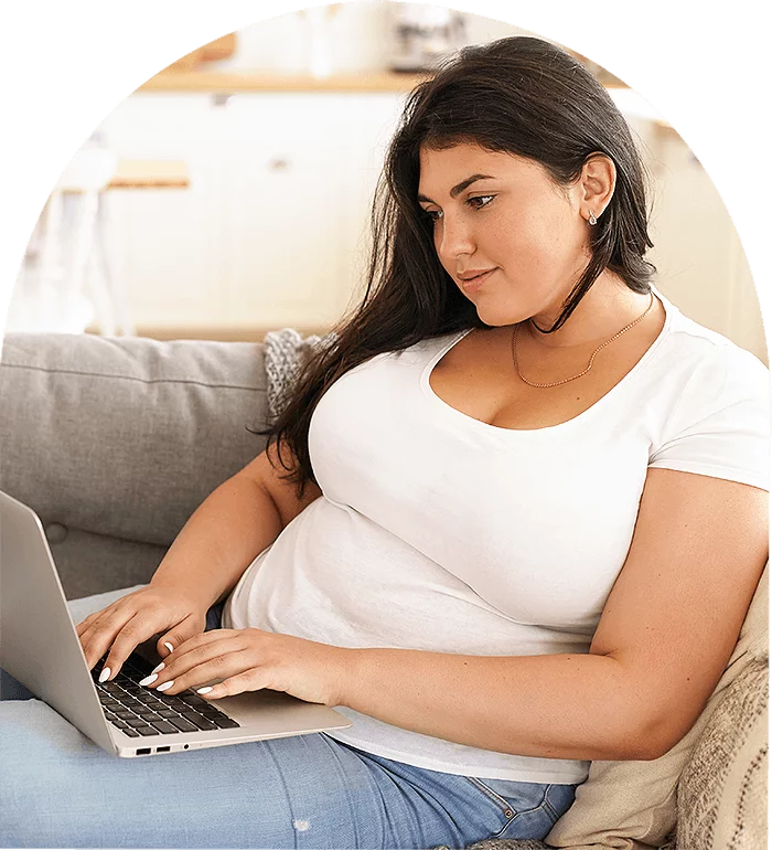 A woman sitting on a couch, looking relaxed and comfortable on a laptop
