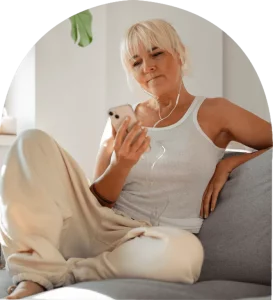 A woman sitting on a couch wearing headphones, looking relaxed and listening to music